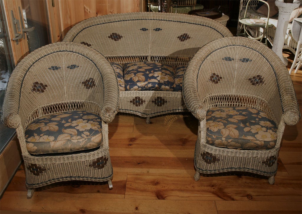 Photo of Art Deco wicker sofa, part of three-piece matching set selling with armchair and rocker pictured separately.  High style curved front sofa in original gray-tan painted finish. Unusual half-rolled arms finished in decorative twisted